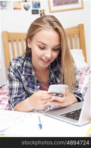 Teenage Girl Using Mobile Phone Whilst Doing Homework