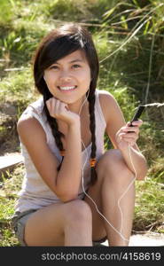 Teenage girl using mp3 player outdoors