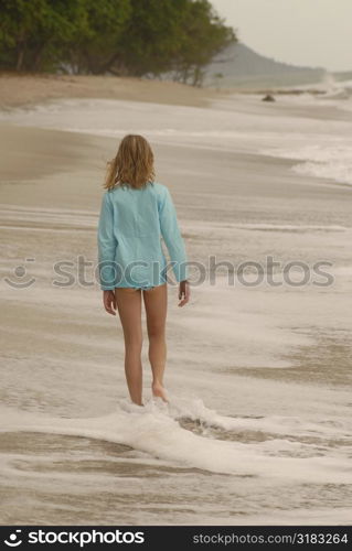 Teenage girl walking down beach