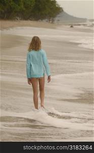 Teenage girl walking down beach