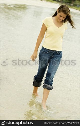 Teenage girl walking on the beach looking down