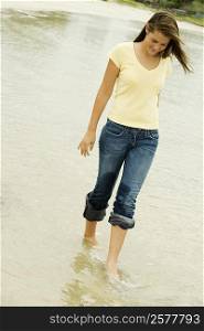 Teenage girl walking on the beach looking down