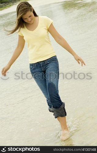 Teenage girl walking on the beach looking down