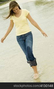 Teenage girl walking on the beach looking down