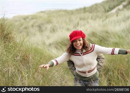 Teenage Girl Walking Through Sand Dunes Wearing Warm Clothing