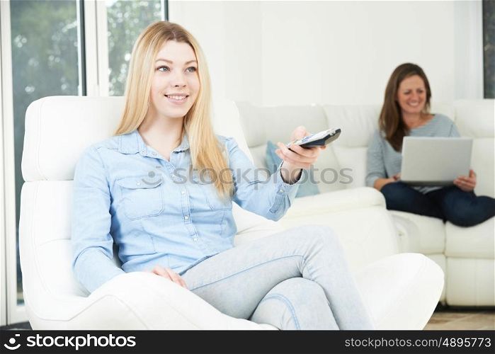 Teenage Girl Watches TV Whilst Mother Works On Laptop