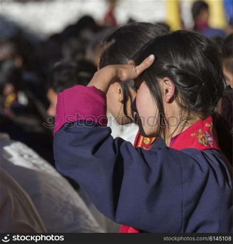Teenage girl watching with shielding eyes, Paro, Bhutan