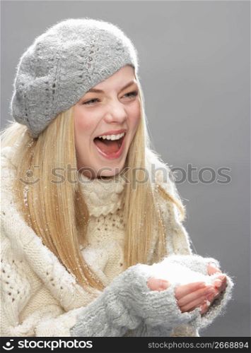 Teenage Girl Wearing Warm Winter Clothes And Hat Blowing Snow In Studio