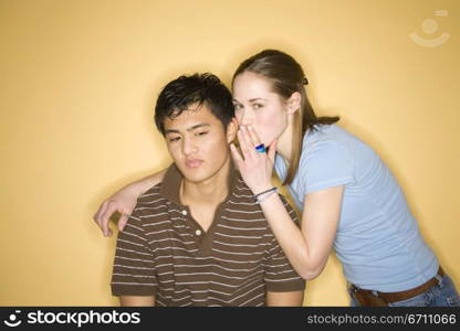 Teenage girl wispering into a teenage boy&acute;s ear