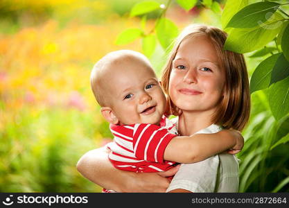 Teenage girl with a baby outdoors.