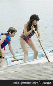 Teenage girl with a boy rowing a boat