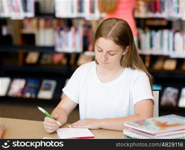Teenage girl with books studying in library. Teenage girl with books