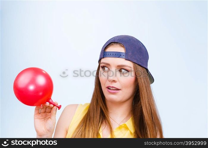 Teenage girl with red balloon.. Teenage girl making funny silly faces. Young trendy woman in jeans cap holding red balloon.