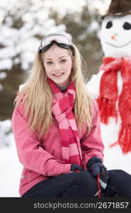 Teenage Girl With Sledge Next To Snowman