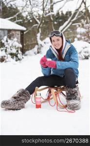 Teenage Girl With Sledge Next To Snowman With Flask And Hot Drink