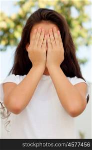 Teenage girl with twelve years old covering her face with the hands