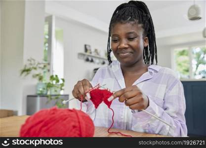 Teenage Girl With Wool Knitting On Table At Home