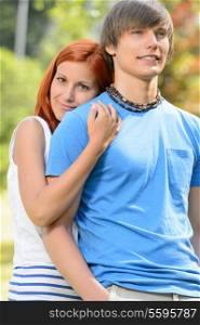 Teenage girlfriend hugging her boyfriend from behind sunny park