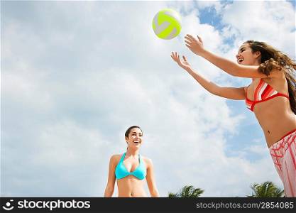 Teenage girls (16-17) playing beach volleyball low angle view