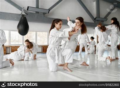 Teenage girls fighting at aikido training in martial arts school. Healthy lifestyle and sports concept. Teenage girls fighting at aikido training in martial arts school