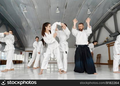 Teenage girls group of students having aikido fight under instructor control. Professional sport and training concept. Teenage girls group of students having aikido fight under instructor control