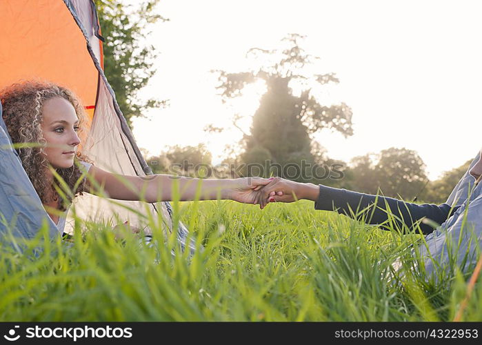 Teenage girls holding hands at campsite