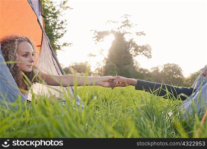 Teenage girls holding hands at campsite