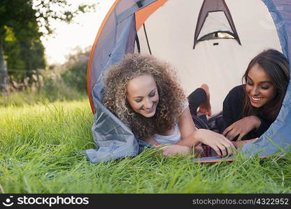 Teenage girls laying in tent at campsite