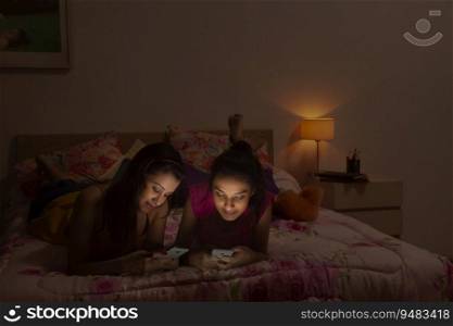 Teenage girls lying on the bed and texting on their mobile phones. 