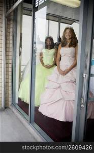 Teenage girls posing as mannequins in dress shop window