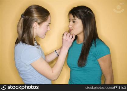 Teenage girls putting on lipstick
