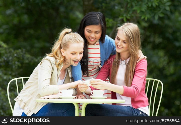 Teenage Girls Sitting At Outdoor cafeWith Mobile Phone