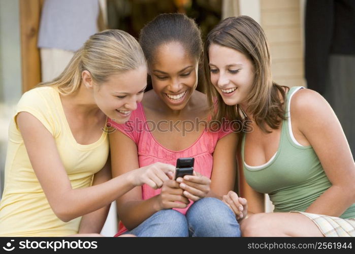 Teenage Girls Sitting Outside Playing With Mobile Phone