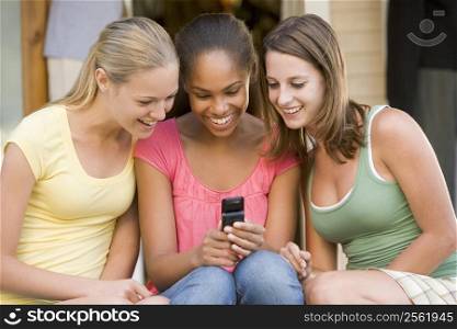 Teenage Girls Sitting Outside Playing With Mobile Phone