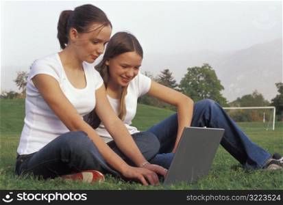 Teenage Girls Using A Laptop On The Soccer Field