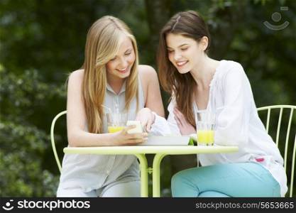 Teenage Girls With Digital Tablet And Mobile Phone In cafe