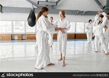 Teenage girls wrestlers practicing basic protection skills during martial arts class in modern sport school. Teenage girls wrestlers practicing basic protection skills during aikido class