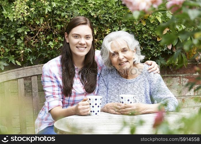 Teenage Granddaughter Relaxing With Grandmother In Garden