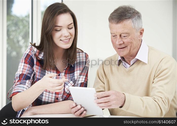 Teenage Granddaughter Showing Grandfather How To Use Digital Tablet