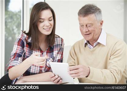 Teenage Granddaughter Showing Grandfather How To Use Digital Tablet