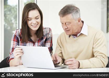 Teenage Granddaughter Showing Grandfather How To Use Laptop Computer