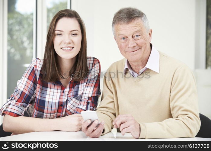 Teenage Granddaughter Showing Grandfather How To Use Mobile Phone