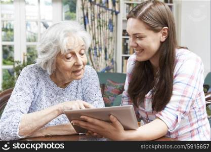 Teenage Granddaughter Showing Grandmother How To Use Digital Tablet