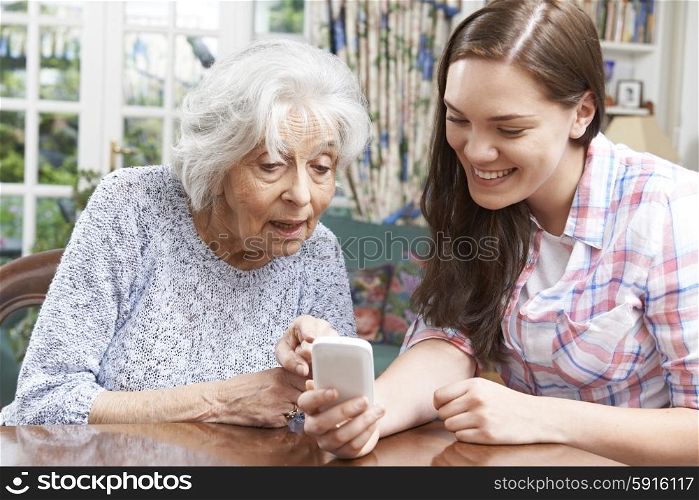 Teenage Granddaughter Showing Grandmother How To Use Mobile Phone