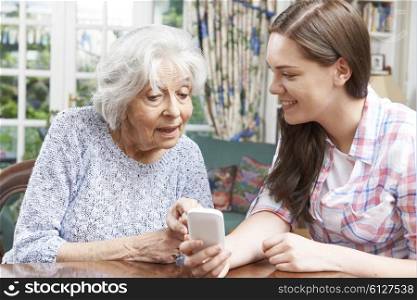 Teenage Granddaughter Showing Grandmother How To Use Mobile Phone