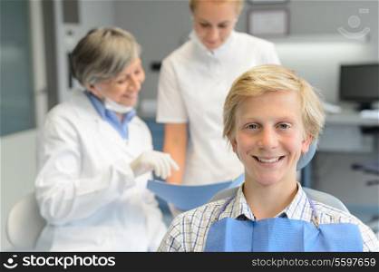 Teenage patient boy, dentist woman with dental assistant at stomatology clinic