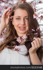 Teenage romantic girl with braces holding blossoming tree branch spring
