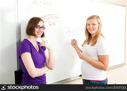 Teenage school girls at the board solving algebra problems.