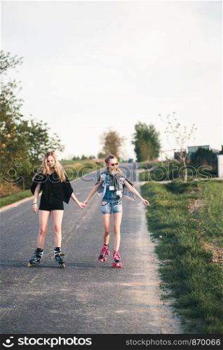 Teenage smiling happy girls having fun rollerskating, spending time together on summer day