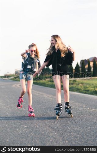 Teenage smiling happy girls having fun rollerskating together on summer day